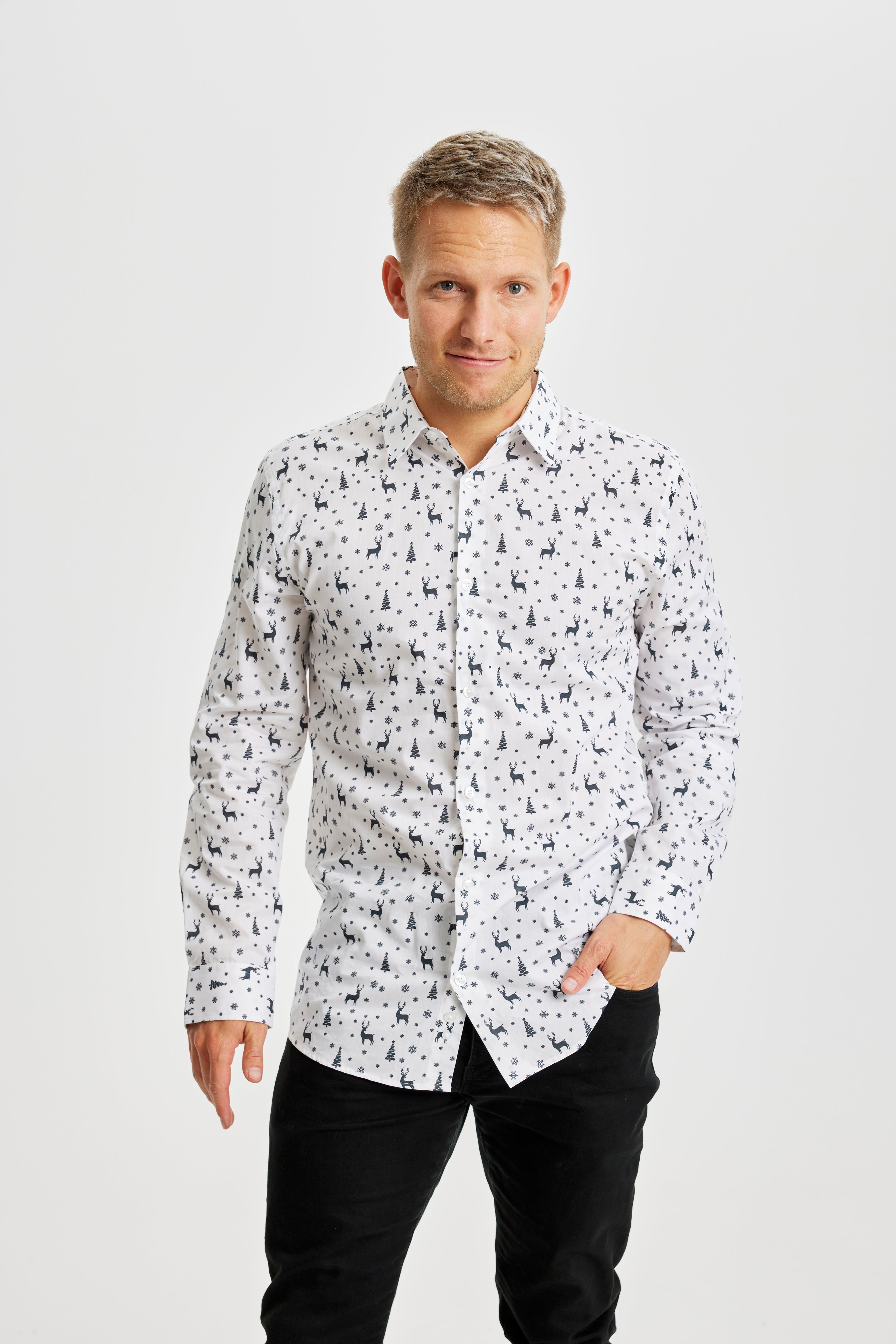 Un homme souriant portant une chemise blanche imprimée de Noël.